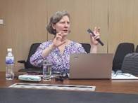 A person sitting at a desk with a computer and a microphone

Description automatically generated